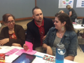 "Dahlstom Middle School SIM Coach Cody Mize collabo-rates with two teachers at the District Literacy Leadership Team meeting."